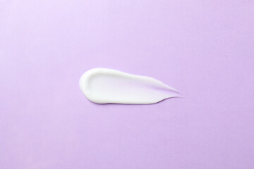 Body cream on violet background, top view