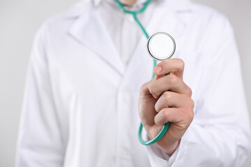 Doctor with stethoscope on light background, closeup