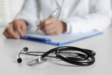 Doctor working and stethoscope on table in hospital, selective focus
