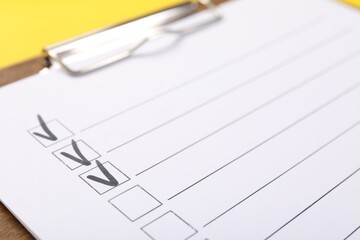 Checklist with marked checkboxes on yellow background, closeup