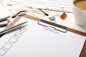 Checklist with marked checkboxes, stationery, glasses, coffee and computer keyboard on white table,...