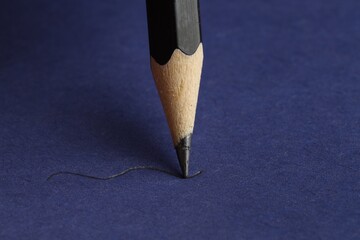 Drawing stroke with graphite pencil on blue background, closeup