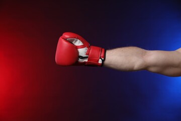 Man with boxing glove fighting on dark background in neon lights, closeup