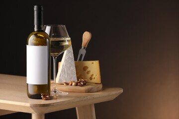 Naklejka premium Tasty wine and snacks on wooden table against brown gradient background. Space for text