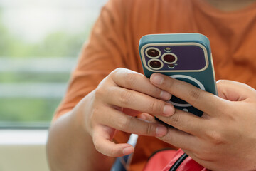 Close-up of a person using a smartphone in public transportation, with focus on the hand and the device. Blurred background