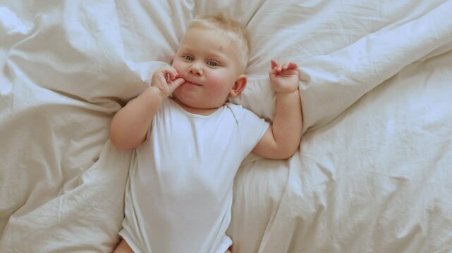 A cheerful baby explores a cozy bed with colorful bedding, showing adorable expressions that capture early childhood happiness and innocence during playful moments
