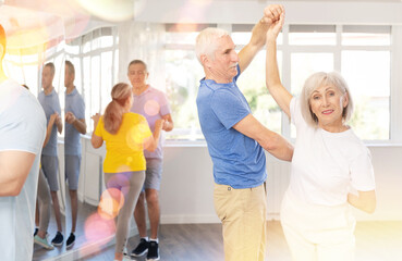 Mature man in dance hall with female partner and dances Latin rumba. Hobby, healthy lifestyle...