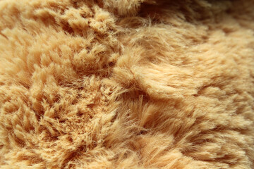 Light brown artificial fur plush fabric material close-up textured background