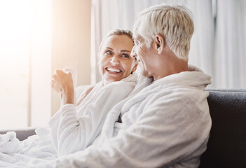 Mature couple, sofa and relax with coffee in gown or robe for luxury spa day together at resort. Senior man or woman with smile for morning, beauty or relaxation treatment on holiday getaway in suite