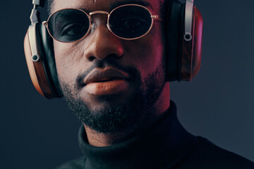 Young Black man wearing stylish sunglasses and headphones, showcasing a confident and modern vibe...