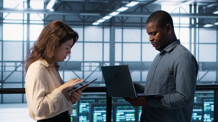 Developers in data center using laptop and tablet, executing security patches, securing firewall....
