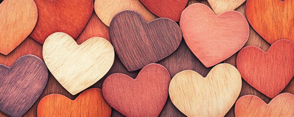 Obraz premium A bunch of wooden hearts are arranged in a pattern. The hearts are of different colors and sizes, and they are all placed on top of a wooden surface