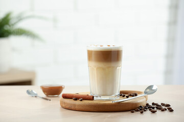 Tasty latte macchiato in glass on wooden table