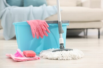 String mop and bucket with cleaning supplies on wooden floor indoors © New Africa
