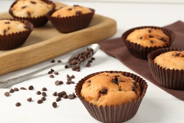 Delicious muffin with chocolate chips on white wooden table, closeup