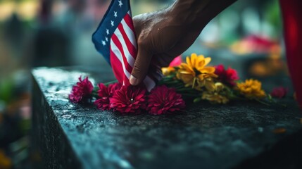 A hand gently places a flag on a memorial with flowers