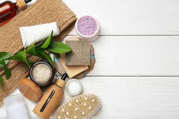Different body care products and green branch on white wooden table, flat lay. Space for text