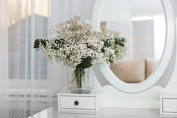 Bouquet of beautiful gypsophila flowers and eucalyptus branches in vase on dressing table near...