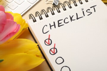 Checklist, keyboard and tulips on beige background, closeup