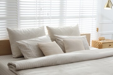 Comfortable bed with soft linens in stylish room, closeup. Interior design