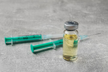 Hepatitis vaccine in glass vials and syringes on grey table, closeup