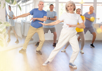 Fototapeta premium Elderly woman dances energetic modern dances in group in studio