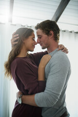 Happy couple, romantic partner and nose touch in bedroom for hug, cute or passion on weekend in...