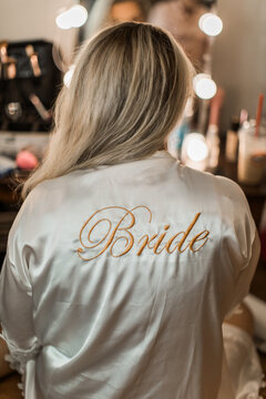 bride getting ready for her wedding day in the morning in a silk white robe 