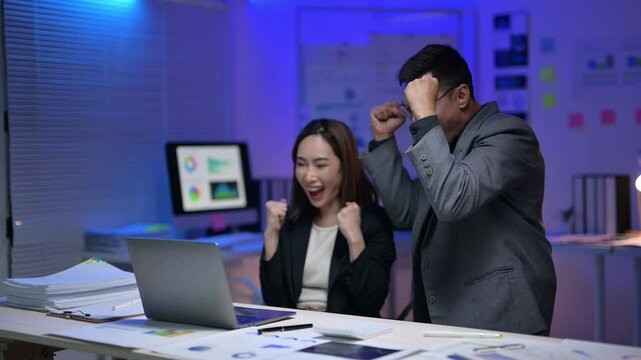 A man and a woman are working together on a laptop. The woman is smiling and the man is looking at her. Scene is positive and collaborative
