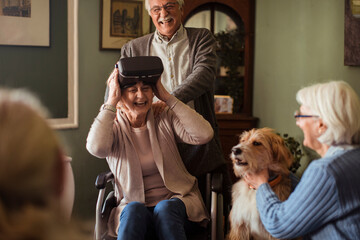 Senior woman in wheelchair using vr headset with friends at home