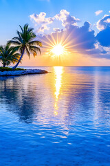 Tropical sunset over calm ocean with palm trees