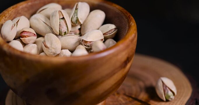 pistachio in their shells with added salt, fried unpeeled pistachio nuts in a wooden bowl with cracked shells