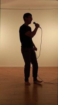 silhueta de homem cantando com microfone 