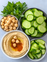 Overhead shot of hummus, chickpeas, and sliced cucumbers