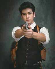 Handsome man holds a gun, ready to shoot in self-defense. This is retro fashion photography from the 1970s. The Mafia criminal robber or gangster thief controlled the urban area.