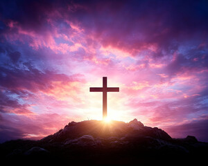 Silhouette of a cross atop a hill at sunset