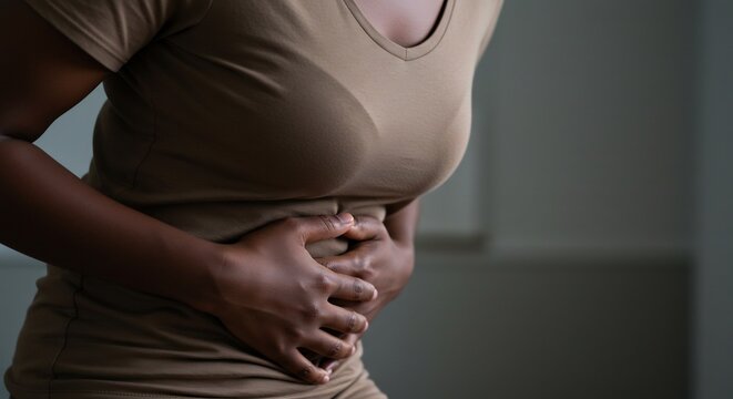 静かな室内、女性が腹部に手を当てる、影のある柔らかい光