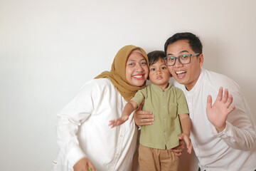 Fototapeta premium Portrait of Asian Muslim parents and son smile and embrace on isolated white background