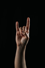 Close-up of a hand showing the rock sign gesture with index and little fingers extended. Popular symbol in music culture, especially in rock and metal genres.