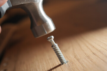 Hammer strikes a screw on a wooden surface during assembly
