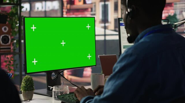 Call center agent using mockup green screen PC, providing step by step guidance to customers. Happy customer center worker using chroma key computer, diagnosing problems for clients, camera A