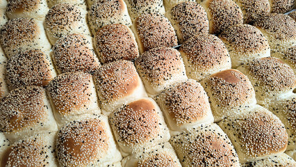 Freshly baked sesame seed rolls displayed in a bakery