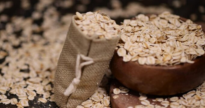 a wooden bowl and a linen bag with oatmeal flakes for making porridge, scattered dry cereal flakes from oats