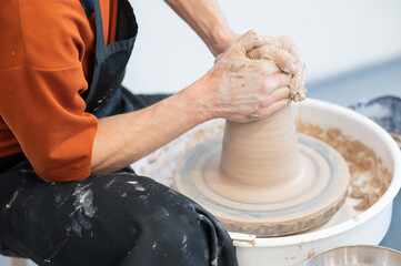 Close-up of a potter's hands working on a pottery wheel. 