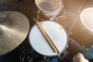 Drum set with drumsticks on snare drum in rehearsal studio, music production or musical education, sound recording content.