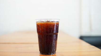 refreshing glass of iced cola sits on a wooden table.