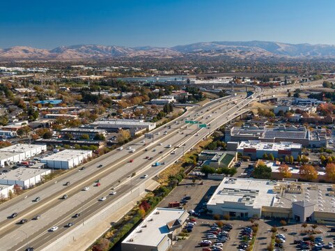 Aerial view of a busy Interstate 680 with cars moving through a suburban area with mountains in the background, Dublin, California, USA. Illustrates transportation and urban planning.