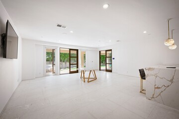 Fototapeta premium A contemporary lounge with marble TV wall, plush pink chairs, and sleek modern decor