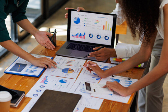 Group of confident business people point to graphs and charts to analyze market data, balance sheet, account, net profit to plan new sales strategies to increase production capacity.	