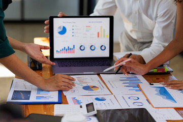 Group of confident business people point to graphs and charts to analyze market data, balance sheet, account, net profit to plan new sales strategies to increase production capacity.	